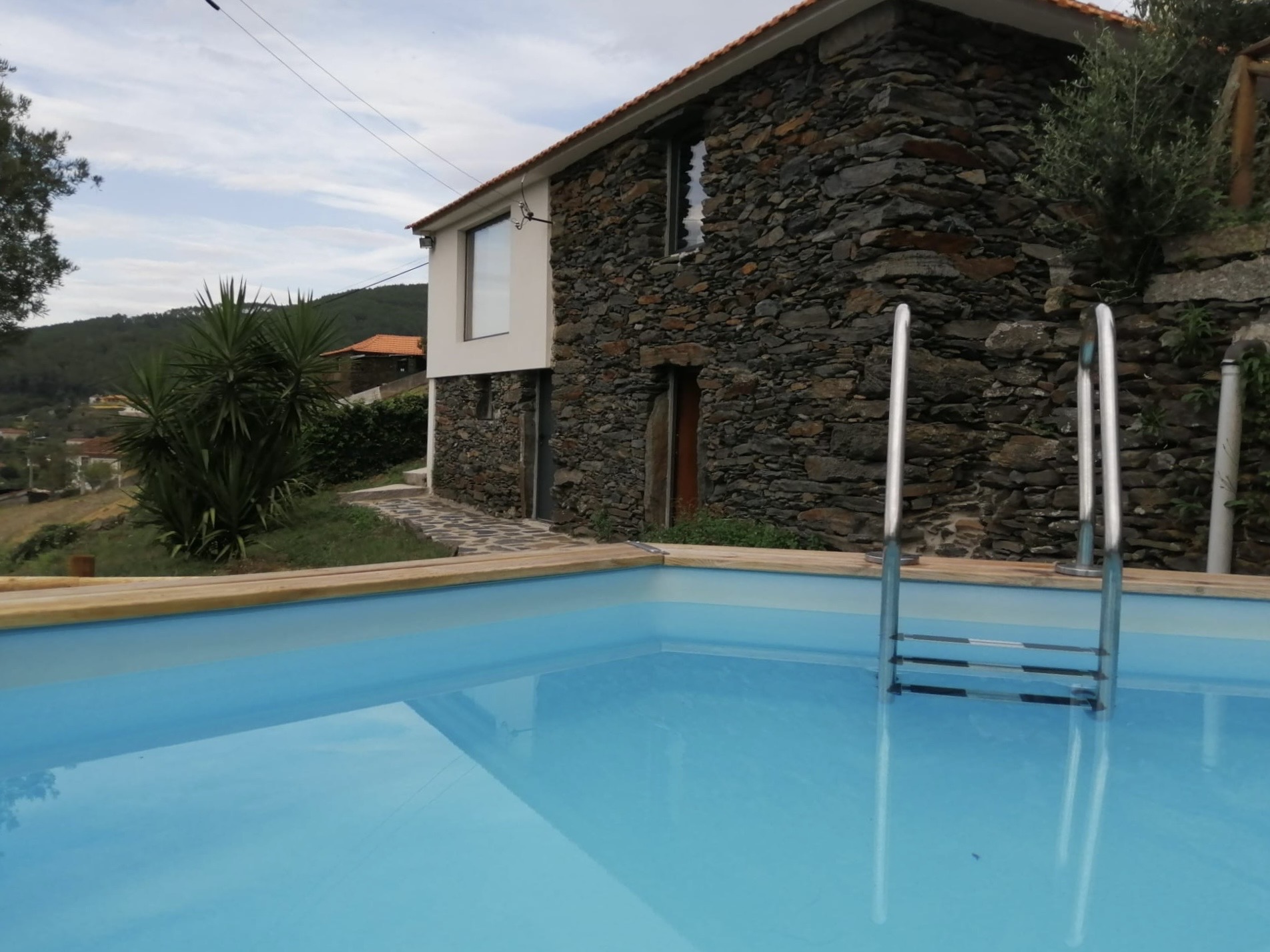 Piscina com a casa de xisto ao fundo